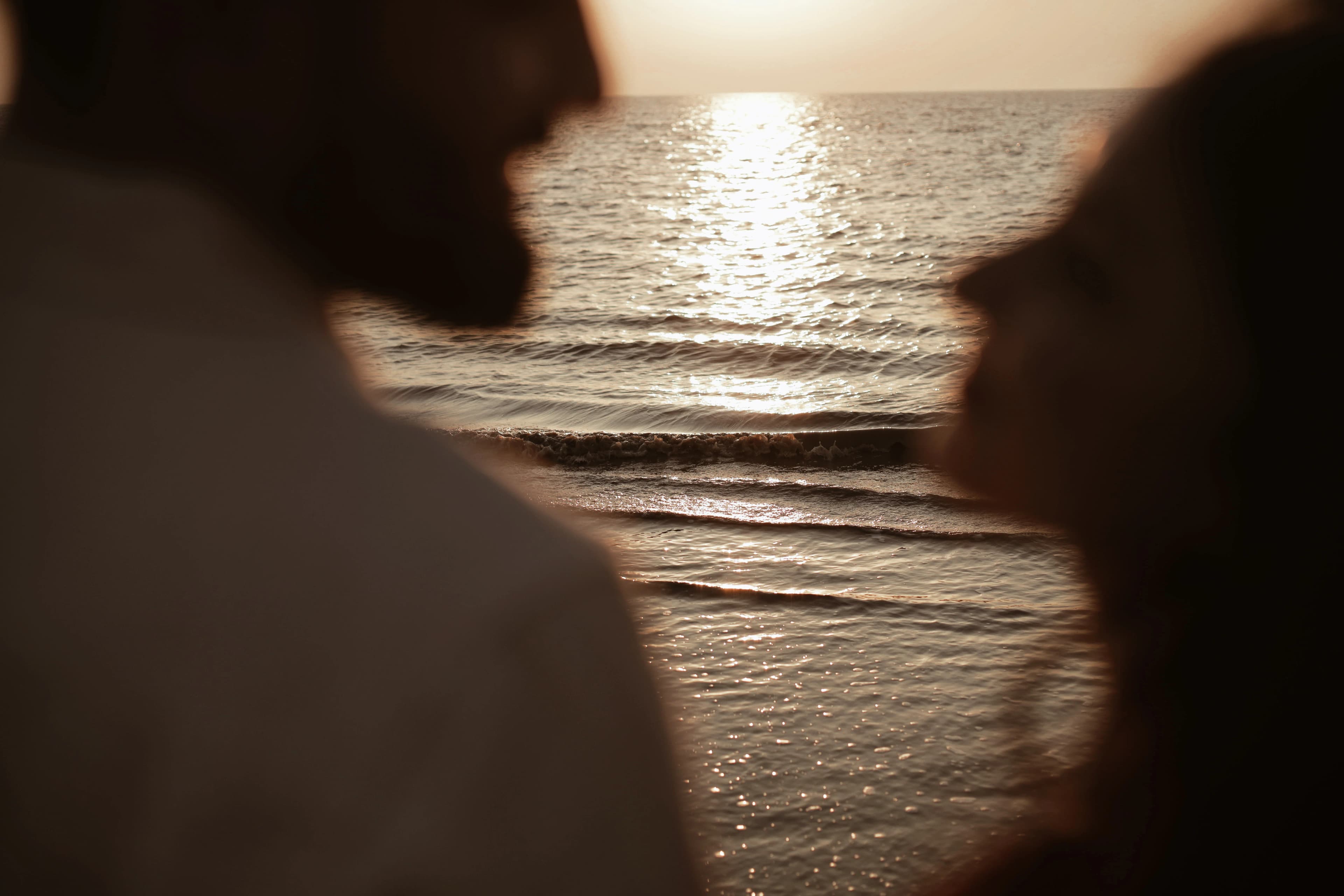 Couple silhouetted face to face against the sea at sunset