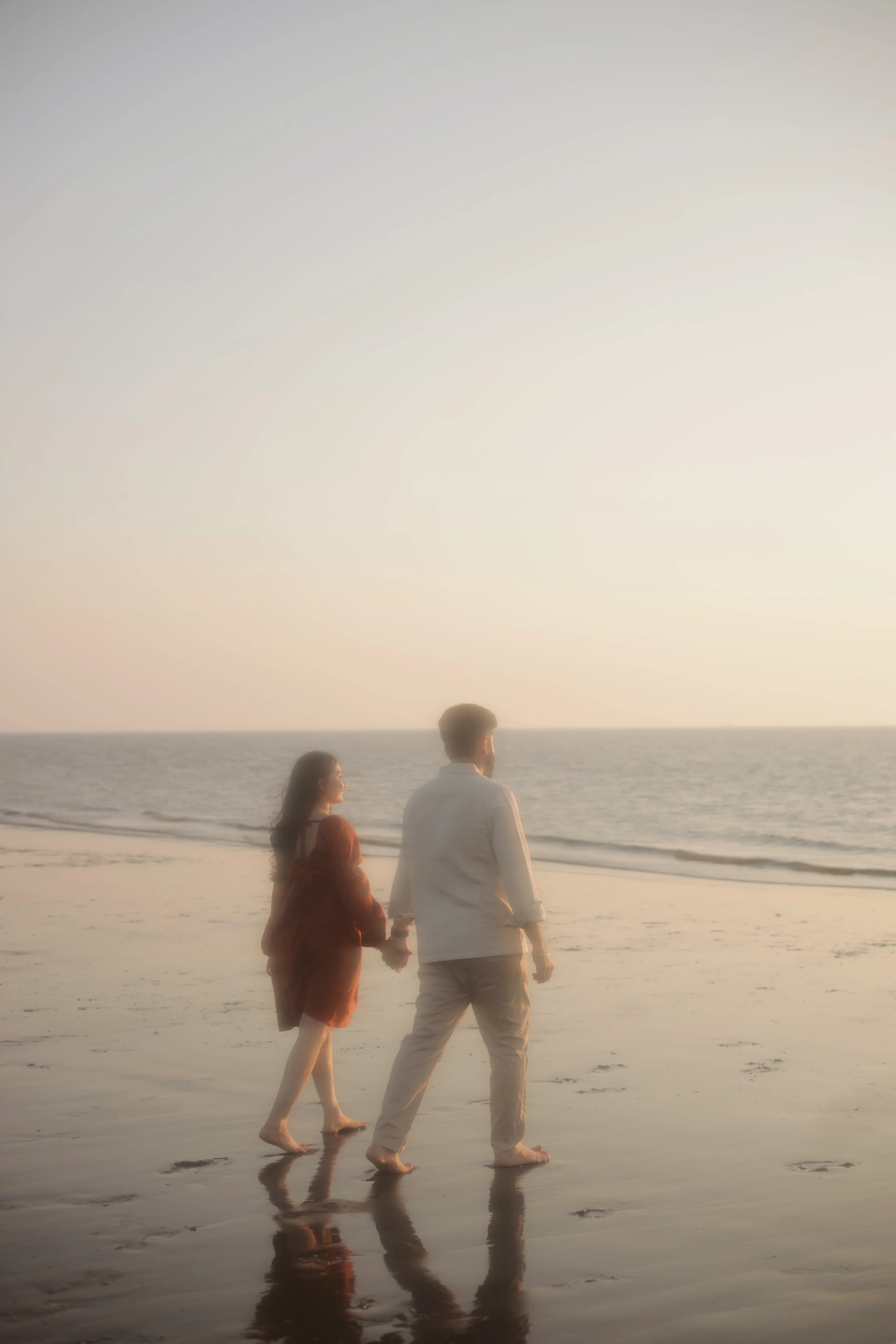 Couple walking hand in hand along the beach at sunset