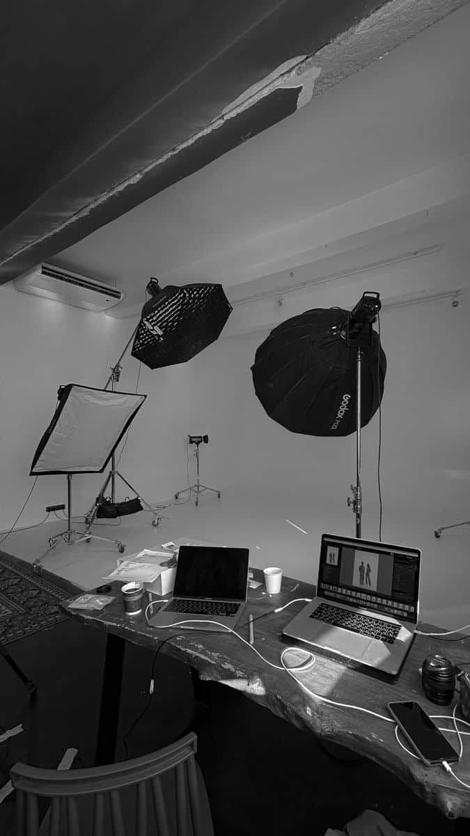 Photography studio with softbox lights and laptops on a desk